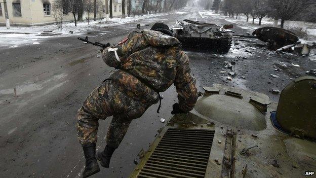 Pro-Russian separatist fighter jumps from an armoured vehicle near a destroyed Ukrainian tank in Uglegorsk, 6 kms southwest of Debaltseve on 9 February 2015