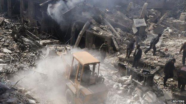 A man operates an excavator to remove rubble at a site hit by what activists said were airstrikes by forces loyal to Syria's President Assad in Douma