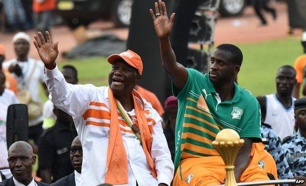 Ivorian President Alassane Ouattara and Ivory Coast captain Yaya Toure wave at the crowd