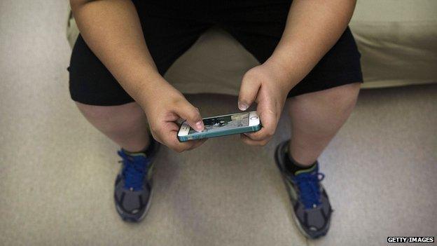 An obese child looking at a mobile phone