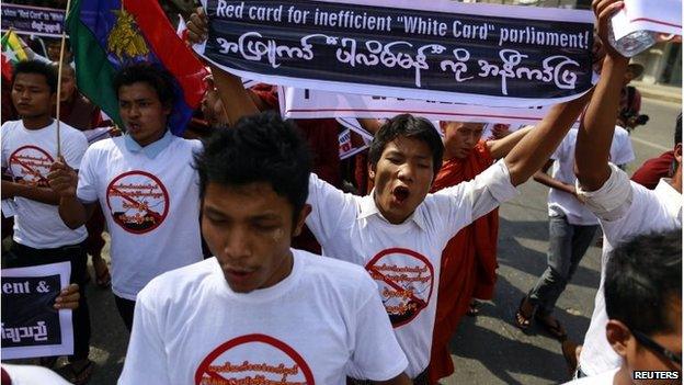 A man holds up a banner during a protest to demand the revocation of the right of holders of temporary identification cards, known as white cards, to vote, in Yangon February 11, 2015