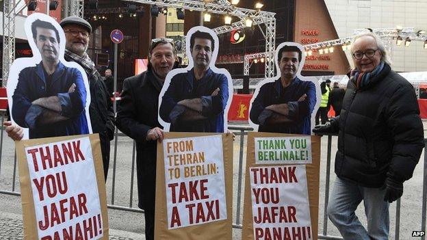 Protesters with posters of Iranian director Jafar Panahi outside the Berlin film festival draw attention to his travel ban as his film Taxi premieres there 06/02/2015