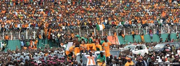 Ivorian President Alassane Ouattara sits next to Ivory Coast's midfielder and captain Yaya Toure as Ivory Coast's players parade in Abidjan
