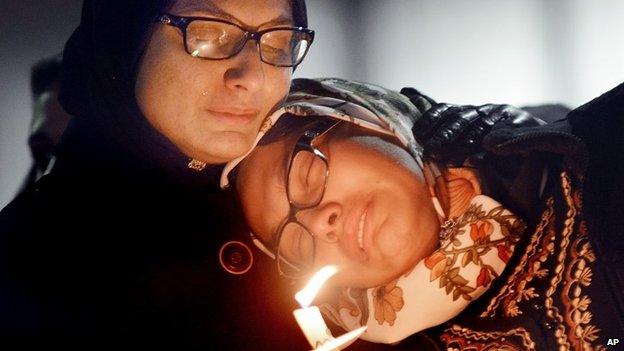 Women mourn during a vigil for three people who were killed at a condominium near UNC-Chapel Hill, Wednesday, Feb. 11, 2015, in Chapel Hill, N.C.