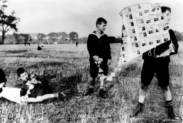 A boy holds a kite made of Deutschmarks