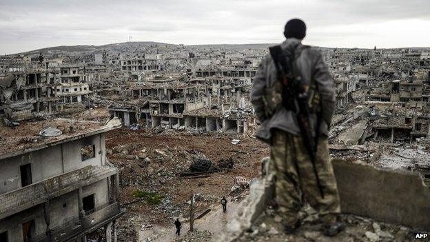 A Kurdish fighter surveys the devastation in Kobane (30 January 2015)