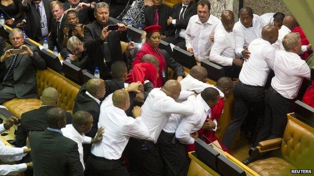 Members of Julius Malema"s Economic Freedom Fighters (EFF) (in red) clash with security officials after being ordered out of the chamber during President Jacob Zuma"s State of the Nation address