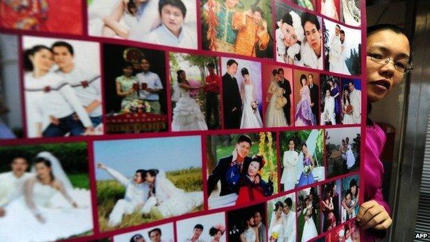 Founder of internet dating site jiayuan.com, Gong Haiyan, poses beside a poster on February 4, 2010 in her Beijing office of photographs of married couples who met on her website.