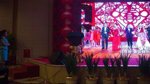 A moderator, left, looks on as a video showing previous galas is displayed at a press conference ahead of the China Central Television's annual hours-long Spring Festival Gala held in Beijing, Monday, Feb. 2, 2015.