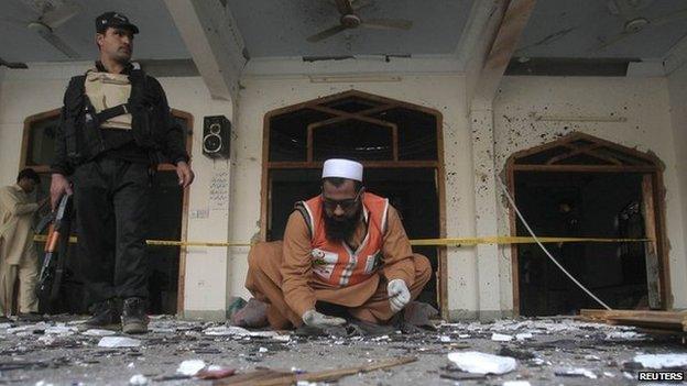 A rescue worker collects evidence from the site of an explosion in a Shia mosque in Peshawar 13 February 2015