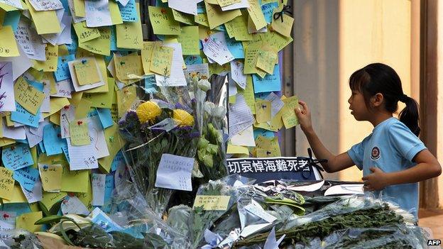 A young girl places a message at a ferry pier to commemorate the victims of the boat collision in Hong Kong on 4 October 2012