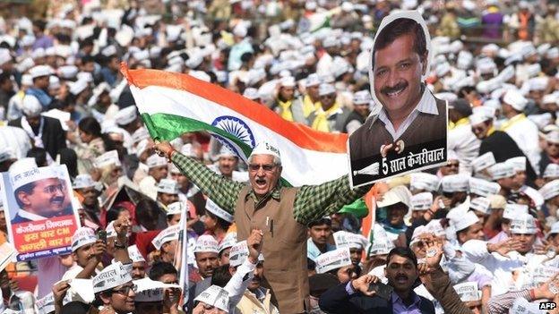 Supporters of the Aam Aadmi Party (AAP) shout slogans as they watch leader Arvind Kejriwal being sworn in as Delhi chief minister at Ramlila Grounds in New Delhi on Saturday