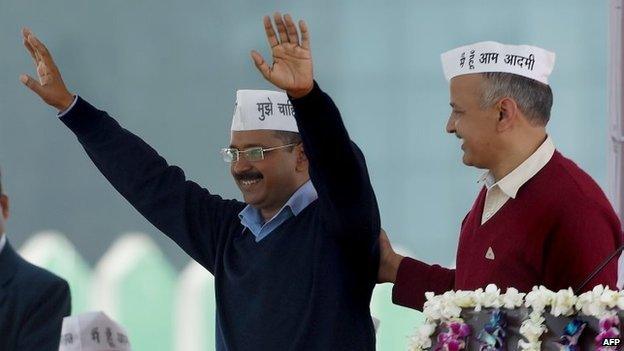 Aam Aadmi Party (AAP) president Arvind Kejriwal (L) greets his supporters as fellow Minister Manish Sisodia (R) congratulates him during his swearing-in ceremony as Delhi chief minister in Delhi on Saturday