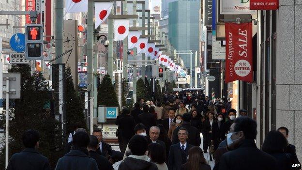 Shoppers walk down a busy street in the Ginza shopping district in central Tokyo