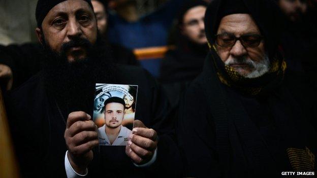 A Coptic clergyman shows a picture of a man whom he says is one of the Egyptian Coptic Christians purportedly murdered by Islamic State (IS) group militants in Libya