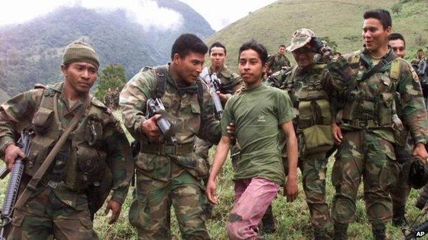 Soldiers escort a 13-year-old captured teenage rebel of the Farc in the mountains of Santander state on 21 December, 2000.