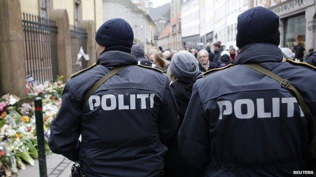 Police officers patrol near a memorial site for the victims of the deadly attacks in front of the synagogue in Krystalgade in Copenhagen, 16 February 2015