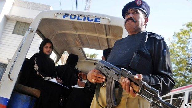 A member of the Pakistani security services escorts health workers as they administer Polio vaccines to children in Karachi, Pakistan, 27 January 2015.