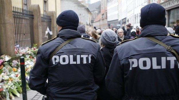 Police officers patrol near a memorial site for the victims of the deadly attacks in front of the synagogue in Krystalgade in Copenhagen, 16 February 2015