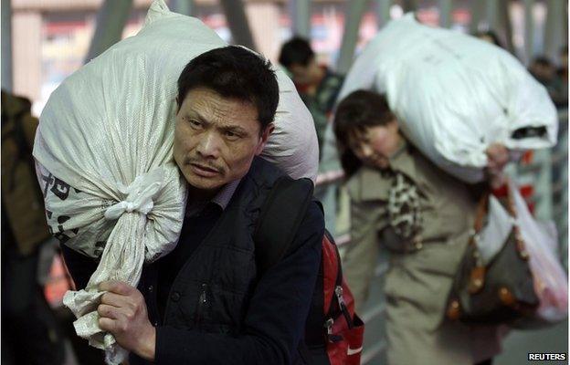 Passengers carry their belongings in sacks as they head to a platform at a railway station in Beijing 17 February 2015.