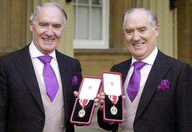 Sir David Barclay (L) and his twin brother Sir Frederick posing after receiving their knighthoods from the Queen at Buckingham Palace