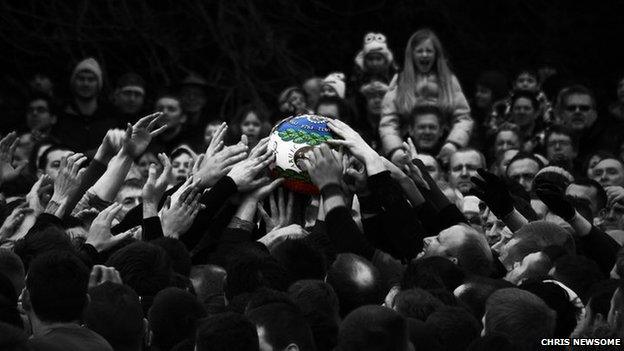 People reaching for the ball at the Ashbourne Shrovetide Football game