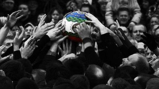 People reaching for the ball at the Ashbourne Shrovetide Football game