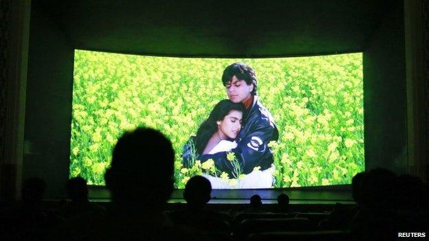 Bollywood actors Shah Rukh Khan (R) and Kajol (L) are seen on the screen during the screening of "Dilwale Dulhania Le Jayenge" (The Big Hearted Will Take the Bride) inside Maratha Mandir theatre in Mumbai December 11, 2014