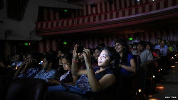 A cinema goer takes a picture as others watch Bollywood movie "Dilwale Dulhania Le Jayenge" (The Big Hearted Will Take the Bride), starring actor Shah Rukh Khan, inside Maratha Mandir theatre in Mumbai December 12, 2014