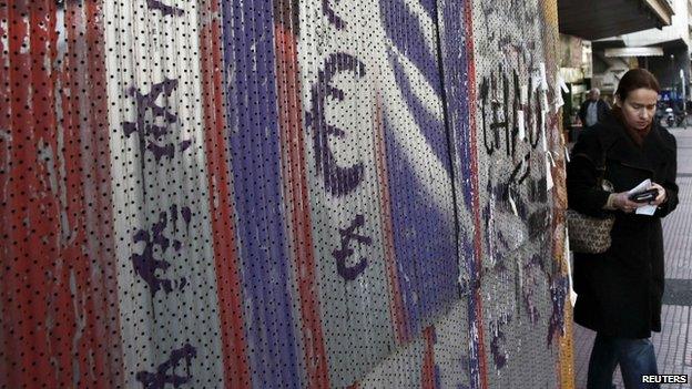 A woman holds her wallet as she walks next to painted euro signs in Athens, 19 February 2015