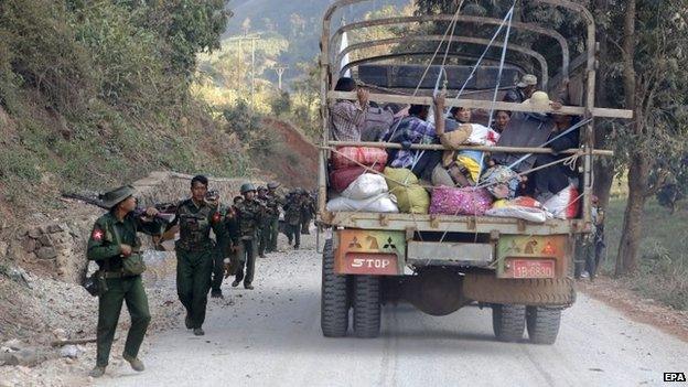 A rescue truck loaded with fleeing locals passes armed military troops near self-administered Kokang capital Laukkai, northern Shan State, Myanmar, 17 February 2015