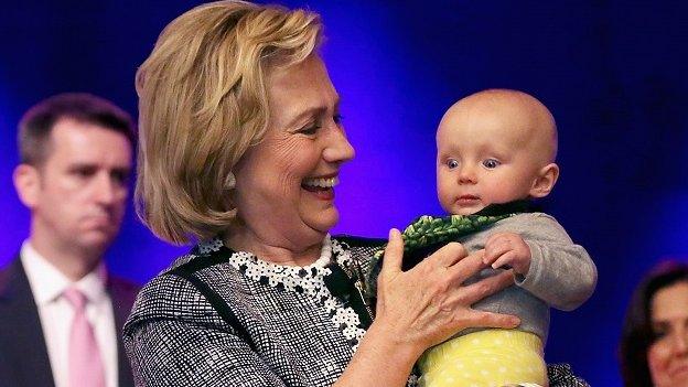 Hillary Clinton holds a baby.