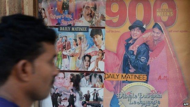 In this photograph taken on December 5, 2014, an Indian cinemagoer walks past a poster of a screening of Bollywood film Dilwale Dulhania Le Jayenge