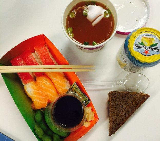 Sushi, mison soup, canned drink and a sandwich