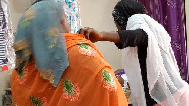 A shop assistant measures a customer at Alhayat Global Synergy in Kano, Nigeria - February 2015