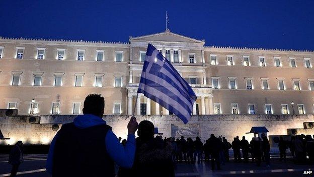 A man holds a Greek flag in front of the Greek parliament in Athens as people gather in support of their government - 20 February 2015