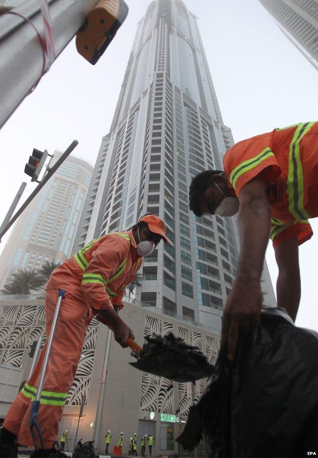 Workers clean up debris from the Torch skyscraper in Dubai