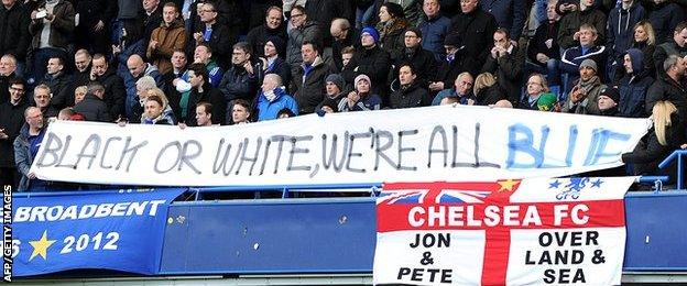 Fans holding a banner reading: "Black or white, we're all blue."