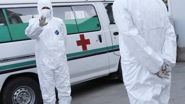 In this Oct. 27, 2014 photo, medical personnel in protective suits stand by an ambulance at the Sunan International Airport in Pyongyang, North Korea.