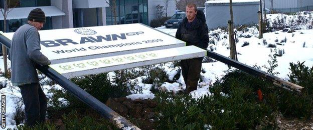 Workers remove a sign outside the Brawn GP factory in Brackley