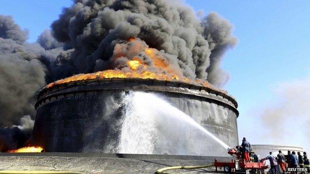 Fire-fighters work to put out the fire of a storage oil tank at the port of Es Sider in Ras Lanufon 29 December 2014