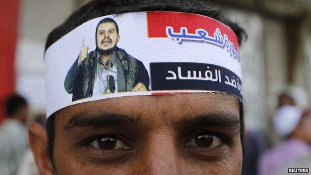 A supporter of the Houthi rebel movements wears a headband bearing a photo of its leader, Abdul Malik al-Houthi, and the slogan "The people's revolution, a revolution against corruption"