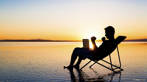 Man in deckchair checking laptop