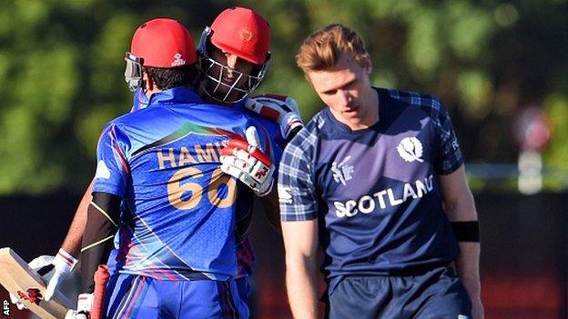 Afghanistan batsmen Hamid Hassan (L) and Shapoor Zadran (C) celebrate as Scotland"s Richie Berrington (R) reacts