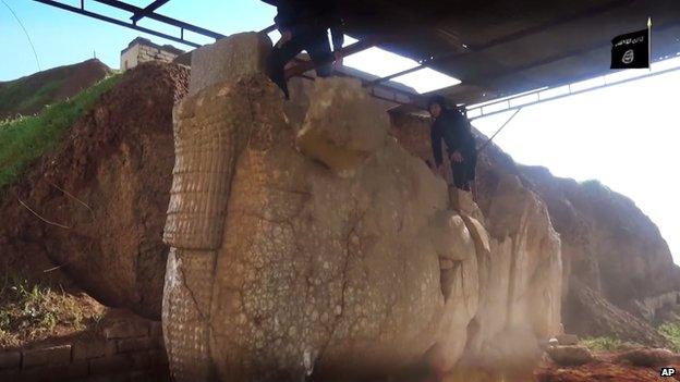 IS militant climbing on top of a statue at the Nerghal Gate, Mosul.