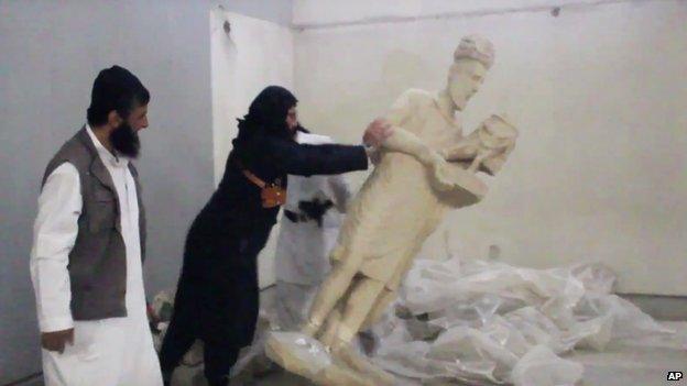 An IS militant appears to push over a statue in Mosul Museum