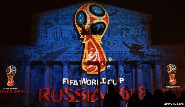 People watch as the facade of the historical Bolshoi Theatre is illuminated with the official emblem of the 2018 FIFA World Cup to be held in Russia in central Moscow in October 2014.