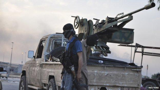 Fighters of the Islamic State of Iraq and the Levant (ISIL) stand guard at a checkpoint in the northern Iraq city of Mosul, June 11, 2014