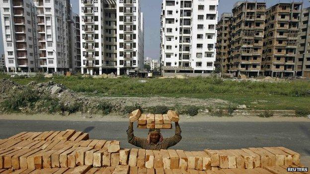 A labourer stacks bricks on his head at the construction site of a residential complex in Kolkata February 28, 2015.