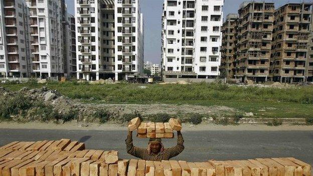 A labourer stacks bricks on his head at the construction site of a residential complex in Kolkata February 28, 2015.